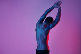 肌肉运动男子赤裸躯干从颜色背景上的回来。画室时尚肖像，性感运动型的家伙