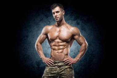 健壯的年輕人在深色背景上的工作室