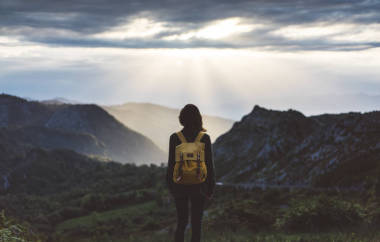 享受夕阳的明亮背包的女孩