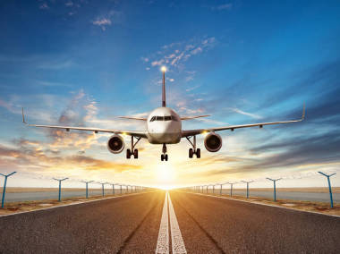 飛機降落到機場跑道在夕陽光圖片