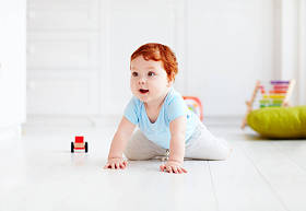 可爱的婴儿宝宝在家里的地板上爬