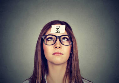 沙钟贴在额头上有思想的女人。时间管理概念