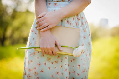 女性特寫(xiě)手在春天公園舉行書(shū)。閱讀概念背景
