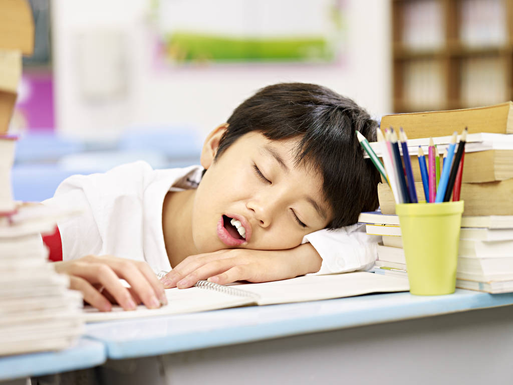 精疲力竭的亚洲学校男孩要在教室里睡着了 精疲力竭的亚洲学校男孩要在教室里睡着了