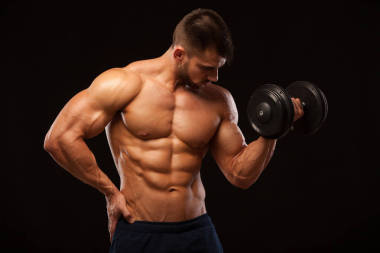 英俊的功率與啞鈴滿懷信心地期待著健壯的男人。與六包、 完美的 abs、 肩膀、 肱二頭肌、 肱三頭肌和胸部孤立與 copyspace 的黑色背景上的強(qiáng)健美