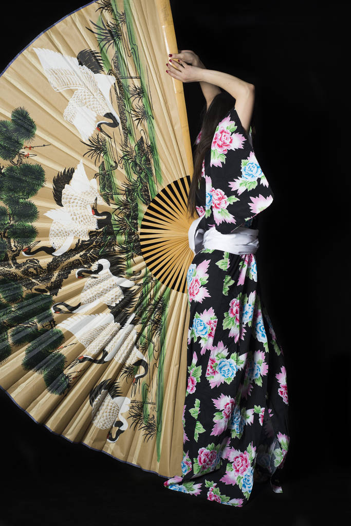 在与上的大风扇的传统日本和服的日本女孩