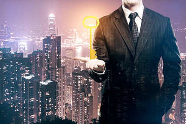 华丽的金钥匙坚持晚上城市背景下的商人。可访问性概念。二次曝光 华丽的金钥匙坚持晚上城市背景下的商人。可访问性概念。二次曝光