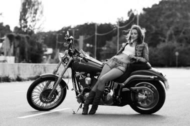 一個(gè)美麗苗條的年輕女子(女孩)站在摩托車上背靠著城市的風(fēng)景