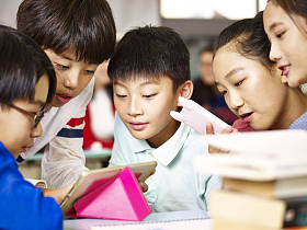 集团的亚洲小学学生玩游戏使用平板电脑