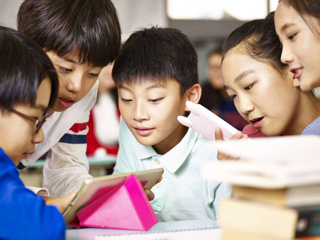 集团的亚洲小学学生玩游戏使用平板电脑