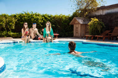 年轻快乐的朋友微笑，大笑，放松，在游泳池里游泳