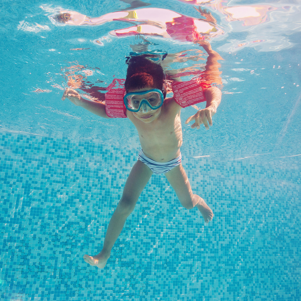 水下的小孩在游泳池与麝香和扶手