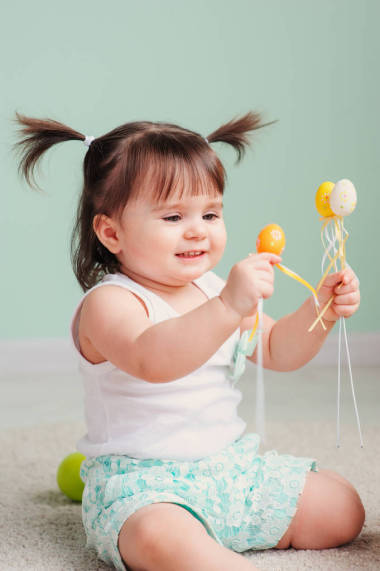 关闭了室内肖像的可爱开心宝贝女孩玩复活节装饰