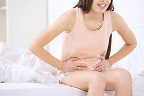 美丽的孕妇患有胃疼在床上