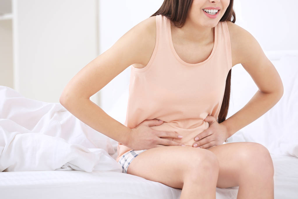美丽的孕妇患有胃疼在床上