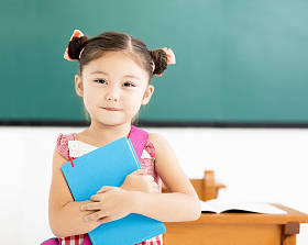 快乐的小女孩举行书在教室里图片