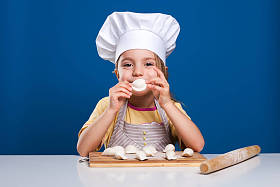 这个小女孩是烹调和准备食物在蓝色背景