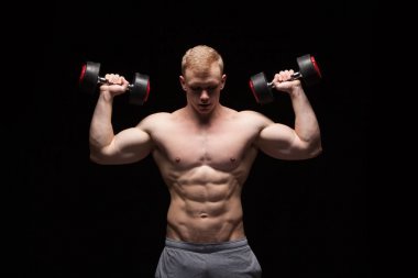 英俊的權(quán)力人健身模型與六包是訓(xùn)練與啞鈴，與 copyspace 的黑色背景上孤立