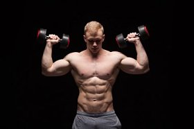 英俊的权力人健身模型与六包是训练与哑铃,与 copyspace 的黑色背景上孤立