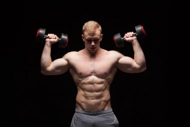 英俊的权力人健身模型与六包是训练与哑铃,与 copyspace 的黑色背景上孤立 英俊的权力人健身模型与六包是训练与哑铃,与 copyspace 的黑色背景上孤立