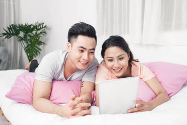 對(duì)夫婦躺在床上和使用平板電腦