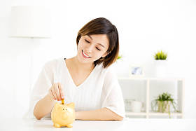 微笑着年轻女人把硬币在存钱罐