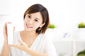 微笑的年轻女子，显示护肤品图片
