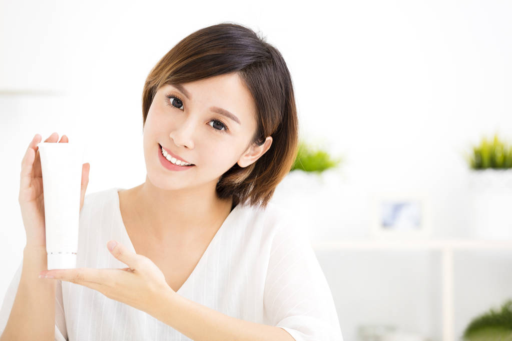 微笑的年轻女子,显示护肤品图片 微笑的年轻女子,显示护肤品图片