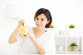 微笑着年轻女人把硬币在存钱罐