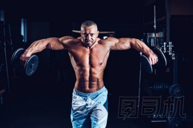 訓(xùn)練與啞鈴健身房在他肩膀的肌肉男