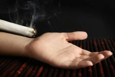 專業(yè)吸煙艾條灸與人的手，在深色背景上