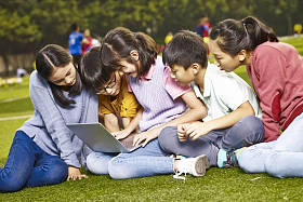 亚洲学生使用笔记本电脑进行户外