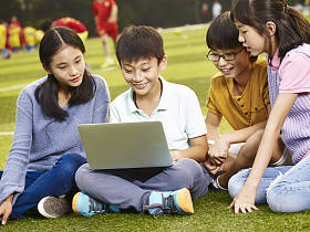亚洲小学儿童使用笔记本电脑进行户外