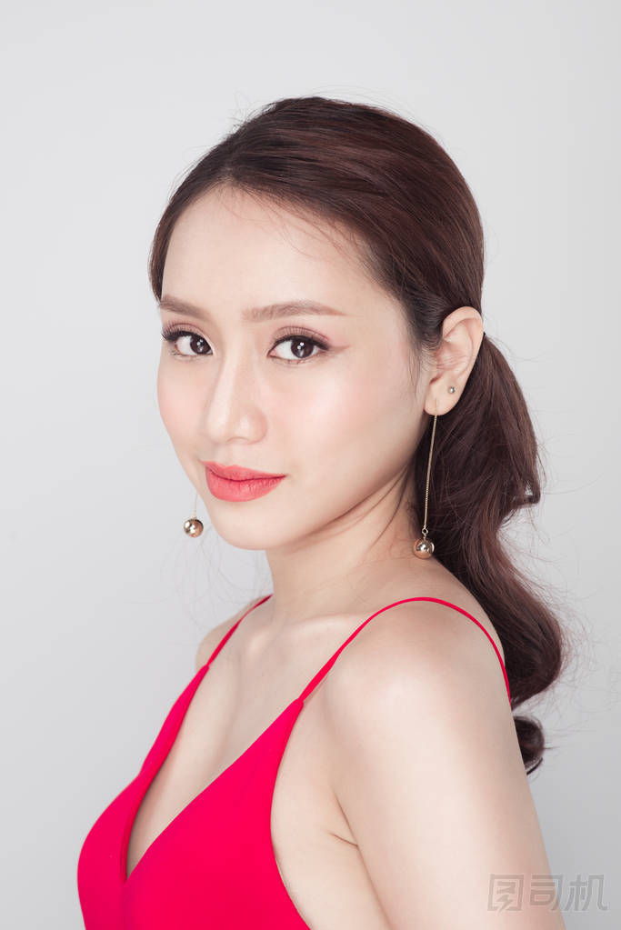 在灰色的背景上穿红裙子的时尚亚洲女人的画像