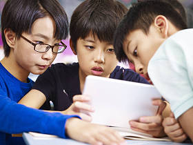 亚洲小学男生一起使用平板电脑
