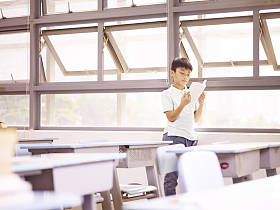 亚洲学生阅读一本书的窗户图片