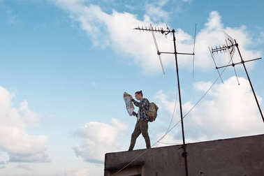 旅行者站在与手中的地图在城市屋顶的边缘 旅行者站在与手中的地图在城市屋顶的边缘