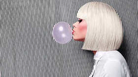 美丽的女孩在白色假发炸毁在粉红的牙床泡沫