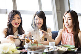 快乐的年轻妇女组吃火锅 照片