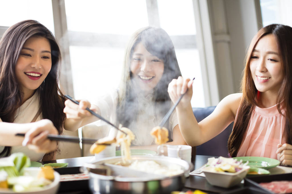 快乐的年轻妇女组吃火锅 图片