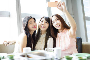  快樂的年輕女孩的朋友，合計自拍照在餐廳