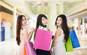 幸福的女人组提着购物袋行走在购物中心