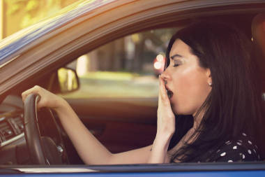 睡眼惺忪的打呵欠女子駕駛她的車經(jīng)過長時(shí)間的旅行. 