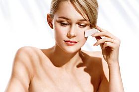 迷人的女孩，在她脸上使用化妆海绵应用基