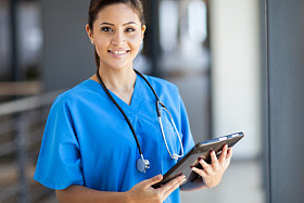 Beautiful young female medical intern with tablet in office By Michael LaHood