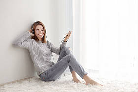 年轻漂亮的女人在家里休息时听听音乐