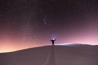 男人用车灯在晚上的雪路的尽头