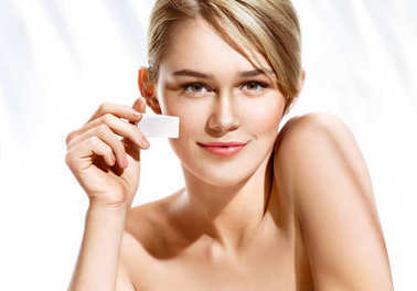 美丽的女人，在她脸上使用化妆海绵应用基