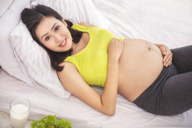 健康怀孕的女人微笑着躺在床上