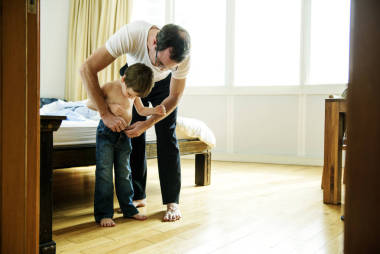 父親幫助兒子裝扮照片